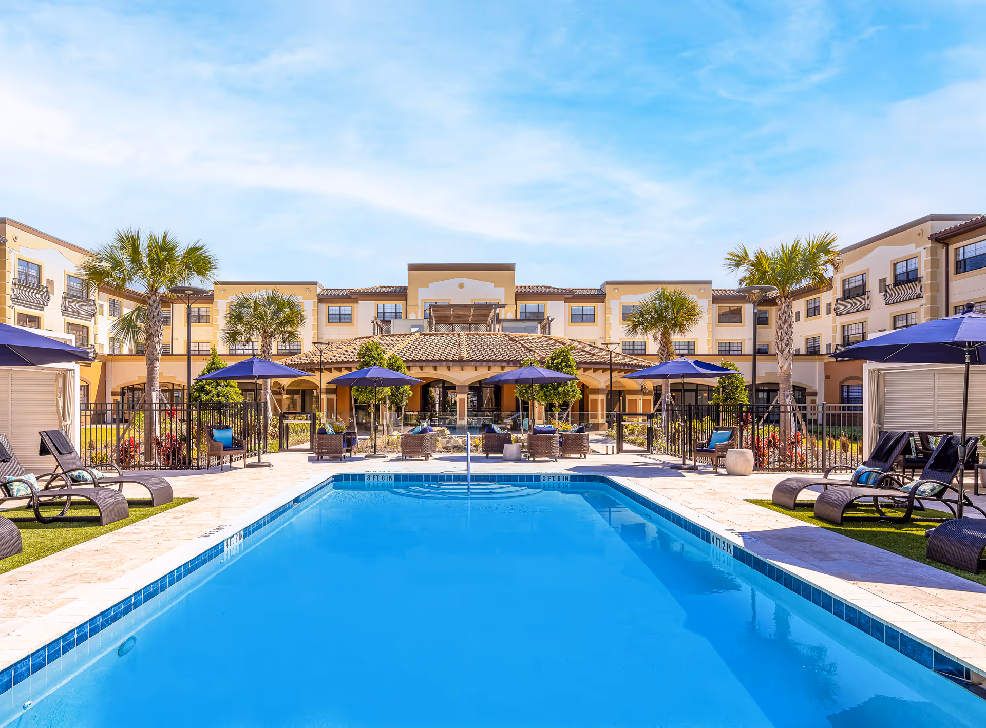 Outdoor pool area at Grand Living Park at Lake Mary with lounge chairs and umbrellas.