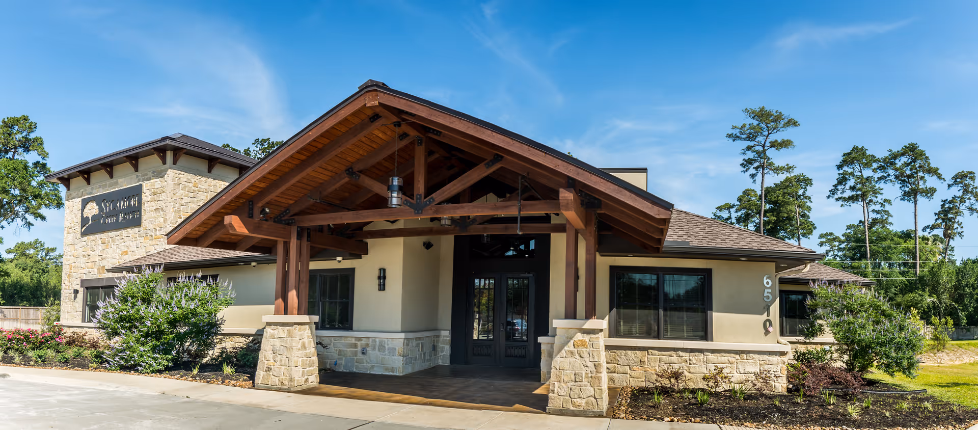 Sycamore Creek Ranch at Cypresswood exterior building entrance with stone pillars and wooden awning