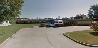 Exterior view of Gilmer Nursing & Rehabilitation building with a parking lot in front.