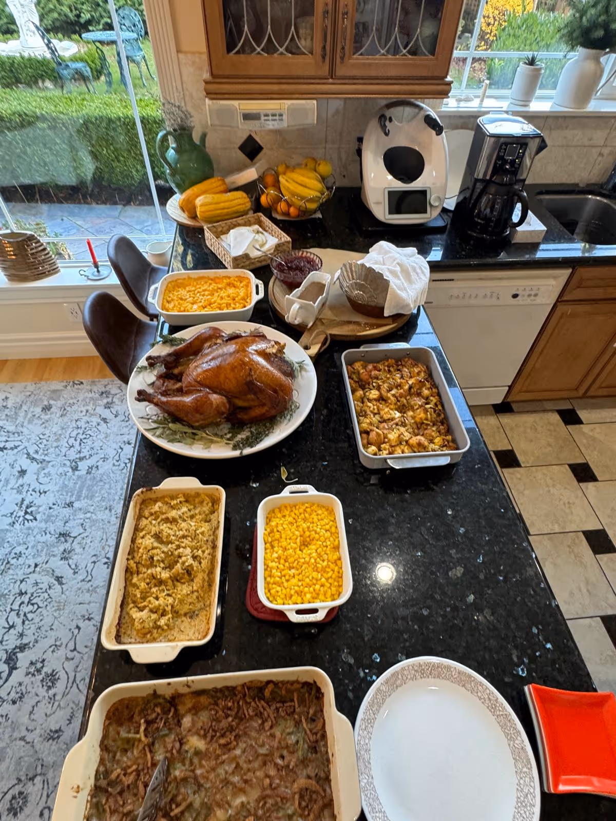 Kitchen island covered with a roasted turkey and multiple side dishes and casseroles ready to serve.