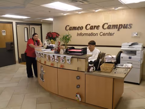 Information center reception desk at Cameo Care Campus with two staff members, holiday decorations, and office equipment.