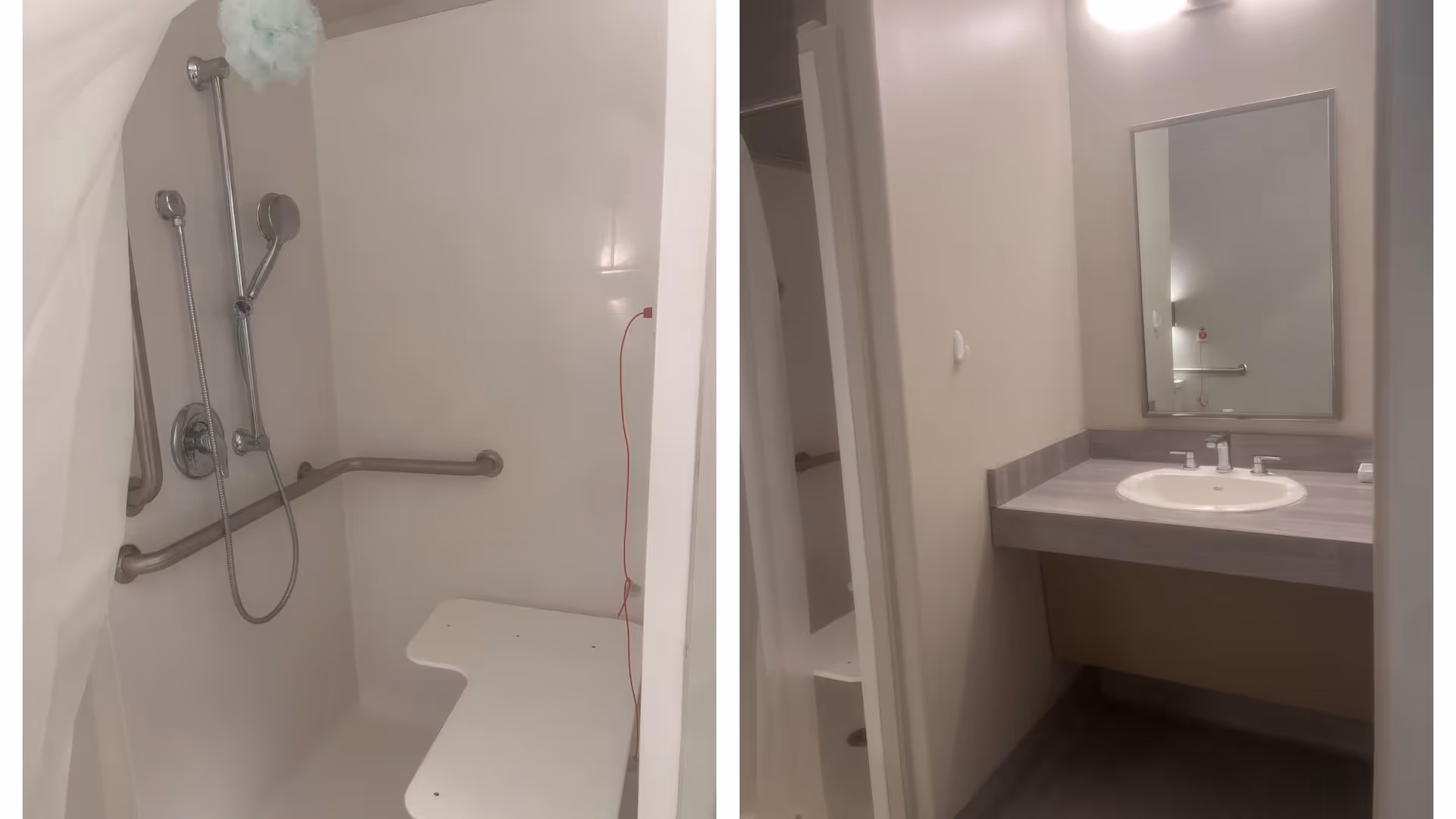A bathroom with a shower area featuring a handheld showerhead, grab bars, and a fold-down shower seat on the left side. On the right side, there is a sink with a countertop, a mirror above it, and a light fixture on the wall.