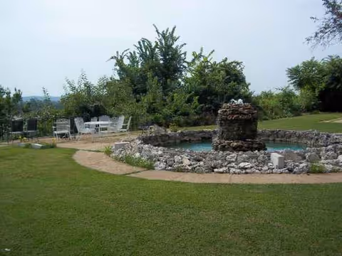 Outdoor courtyard with stone fountain, circular pool, stone seating area, and grassy lawn.