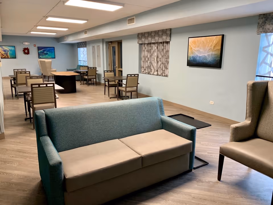 Open communal dining and seating area with sofas, tables and chairs and wall art.