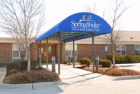 Front entrance of a brick senior living facility with a blue canopy.