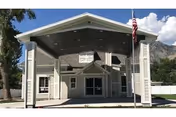 Front entrance of Heritage Gardens of Springville, Utah, with a covered porte-cochere and American flag.