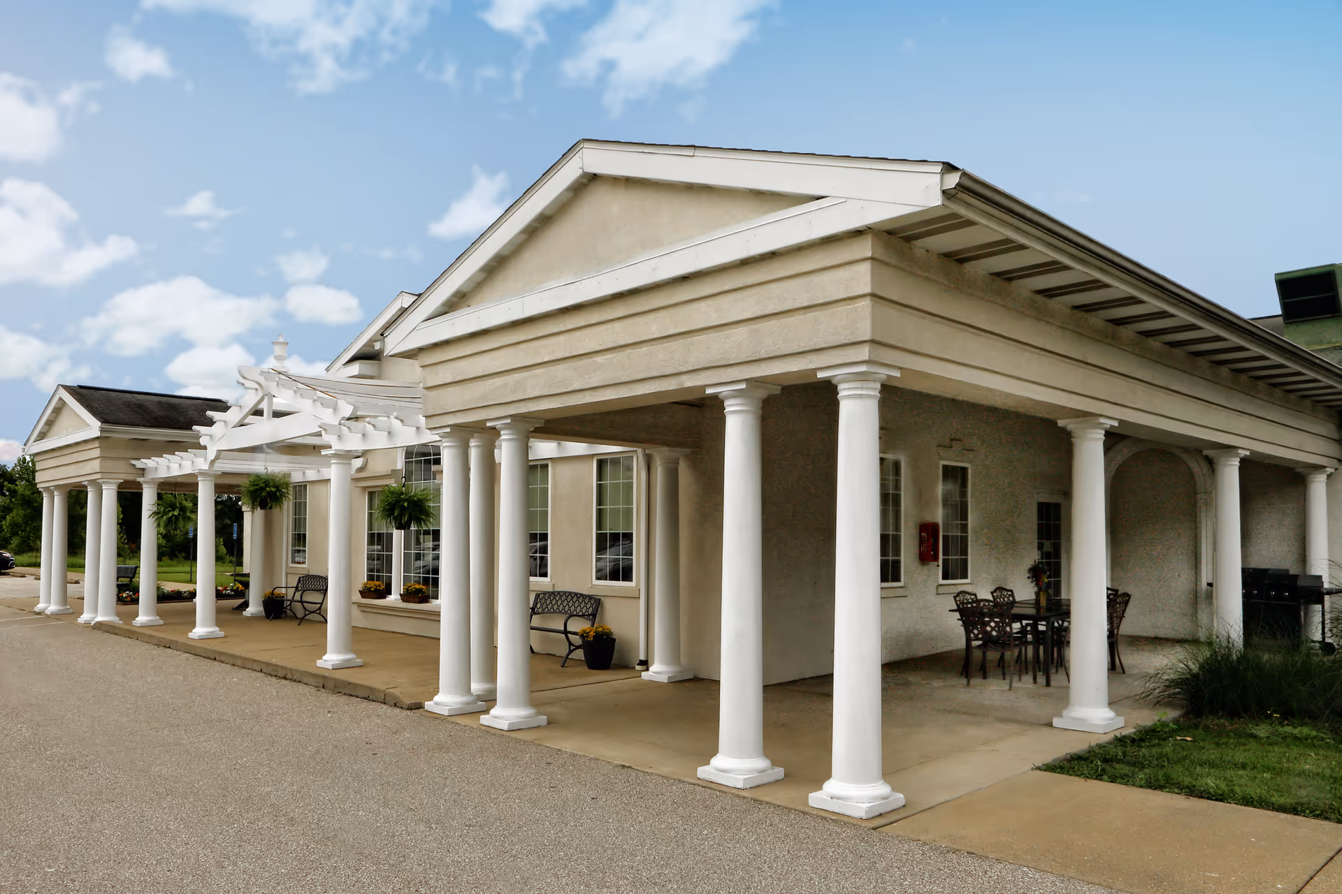 An exterior view of Complete Care at Oak Ridge featuring columns and a seating area.