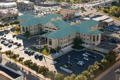 Aerial view of the Gino J Merli Veterans Center, a large multi-story building with green roofs surrounded by parking lots and roads, located in an urban area with other buildings and greenery nearby.