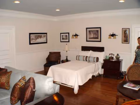 A cozy bedroom in a senior living facility featuring a bed, couch, and nightstands.