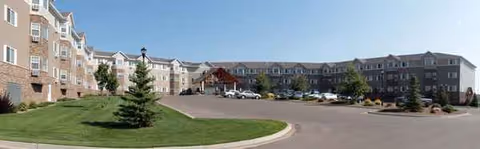 Wide exterior view of Edgewood Bismarck Village buildings, circular drive, and manicured lawn.