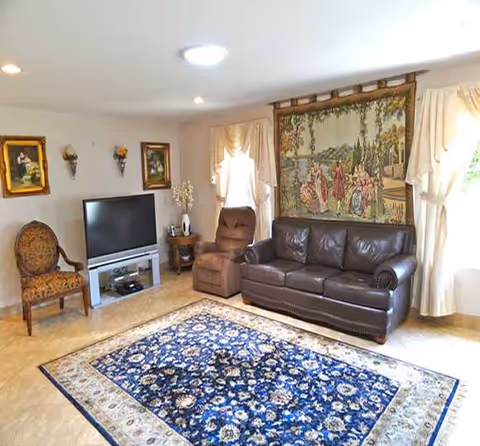Cozy living room at Cheerful Heart Homes with leather sofa, recliner, rug, and wall tapestry.