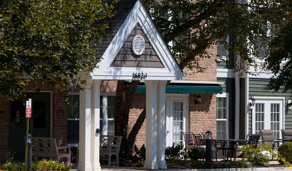Front entrance of Victoria Park showing a white gabled portico with address numbers, brick facade, green awning, and outdoor seating.
