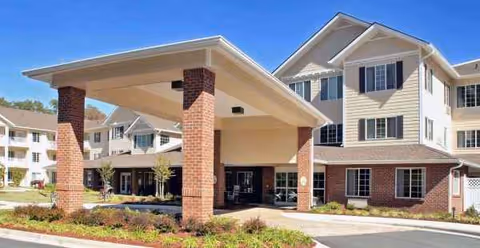 Senior living facility entrance with brick columns and a covered drop-off area.