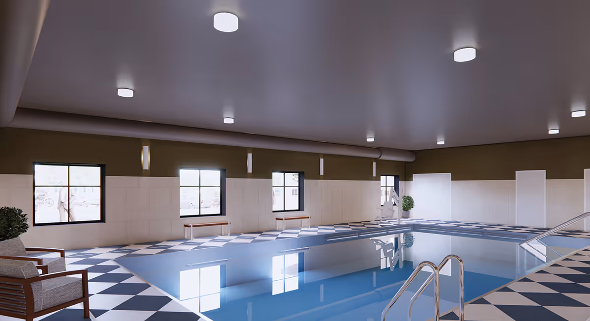 Indoor swimming pool area with checkered black and white tile flooring, several windows along the wall, a pool lift for accessibility, and seating including benches and cushioned chairs. The ceiling has multiple round lights.