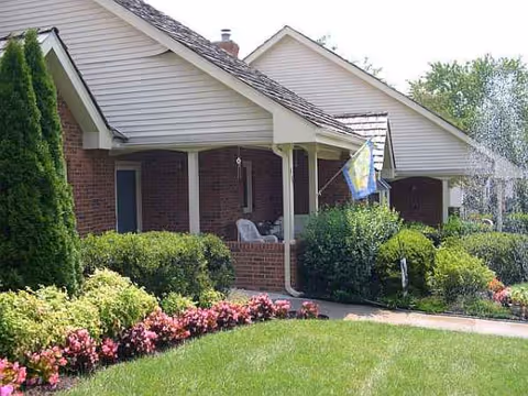 Front view of Summerhill at Stony Point, brick building with a covered porch and colorful landscaping.