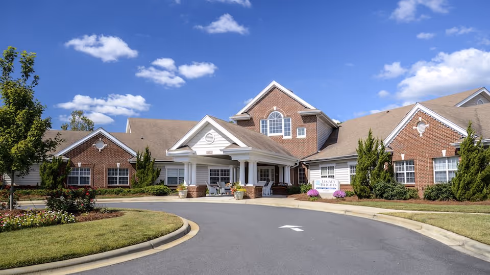 Legacy Heights Senior Living Community exterior with brick facade, entrance, and landscaped circle drive.