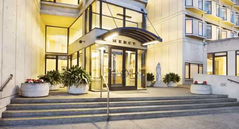 Entrance of Mercy Retirement and Care Center with glass doors, stairs, and planters.