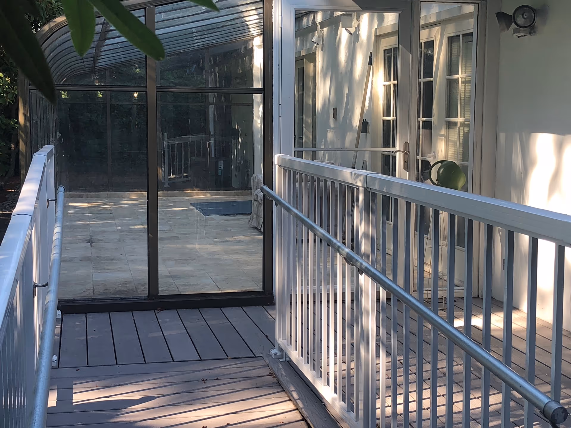 Outdoor deck with white railings, glass doors, and a shaded walkway adjacent to the facility.