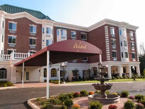 Exterior view of The Bristal Assisted Living at North Hills with building, fountain, and entrance canopy.