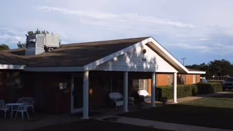 Single-story senior living facility with a covered front porch, white columns, and brick exterior.