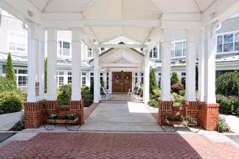 Covered entrance with white columns and brick planters leads to wooden doors at Benchmark at Stamford.