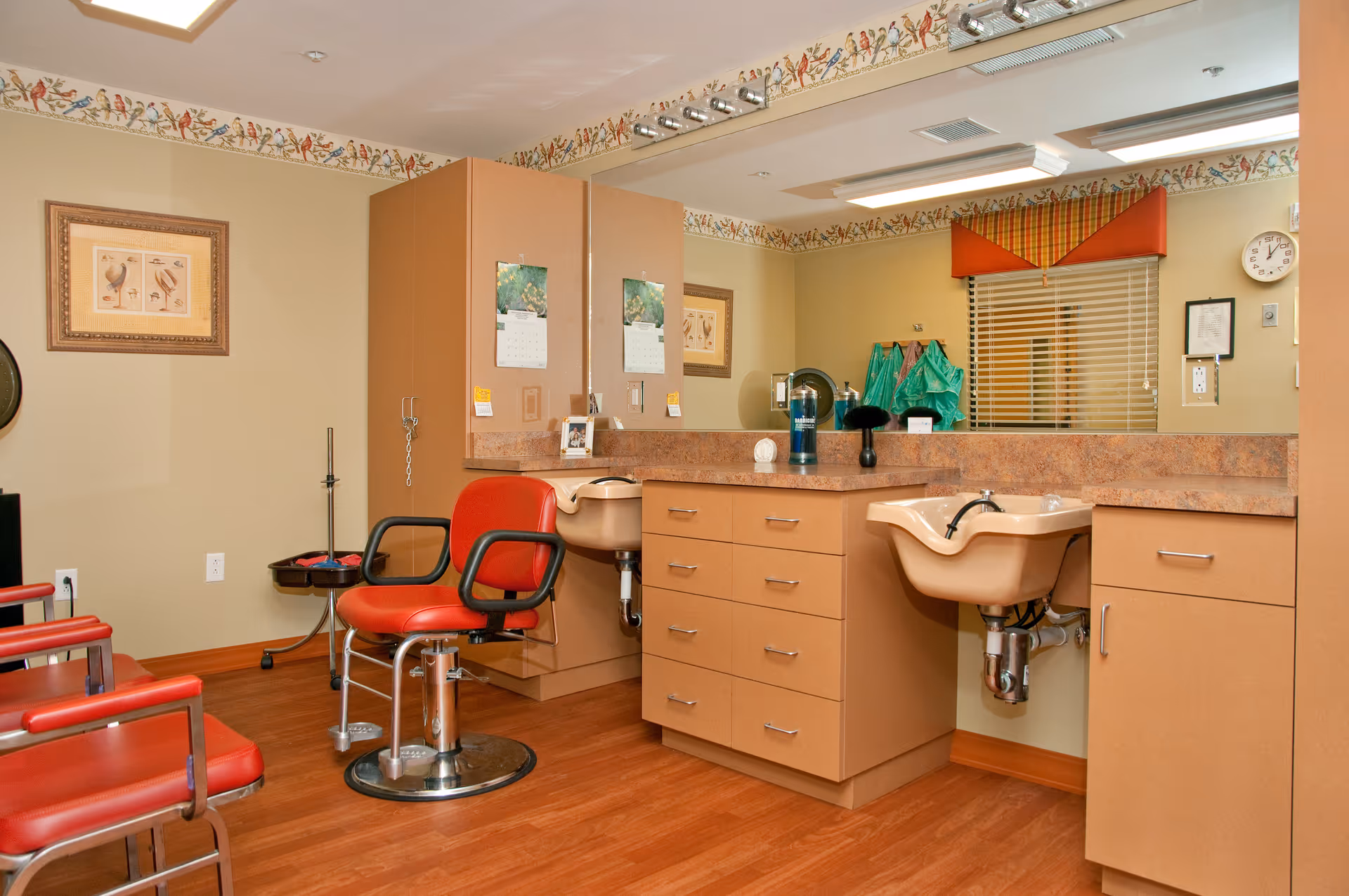 A salon-style interior with red styling chairs, countertops, and wash sinks.