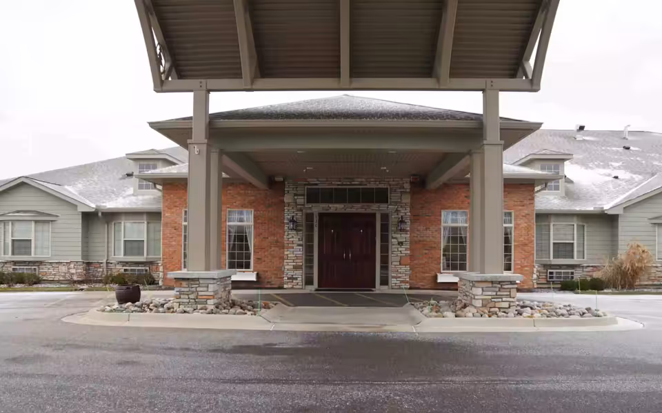 Front entrance of a brick-and-stone senior living facility with a covered entryway.