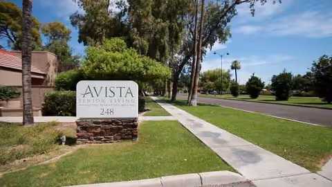 Exterior view of Avista Senior Living Downtown Mesa sign beside a sidewalk.