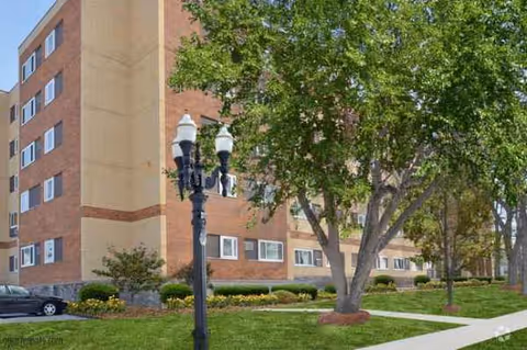 Town Square Apartments exterior with brick building, trees, lawn, and a lamp post.