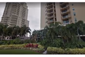 Two tall residential towers with palm trees and manicured landscaping in front.