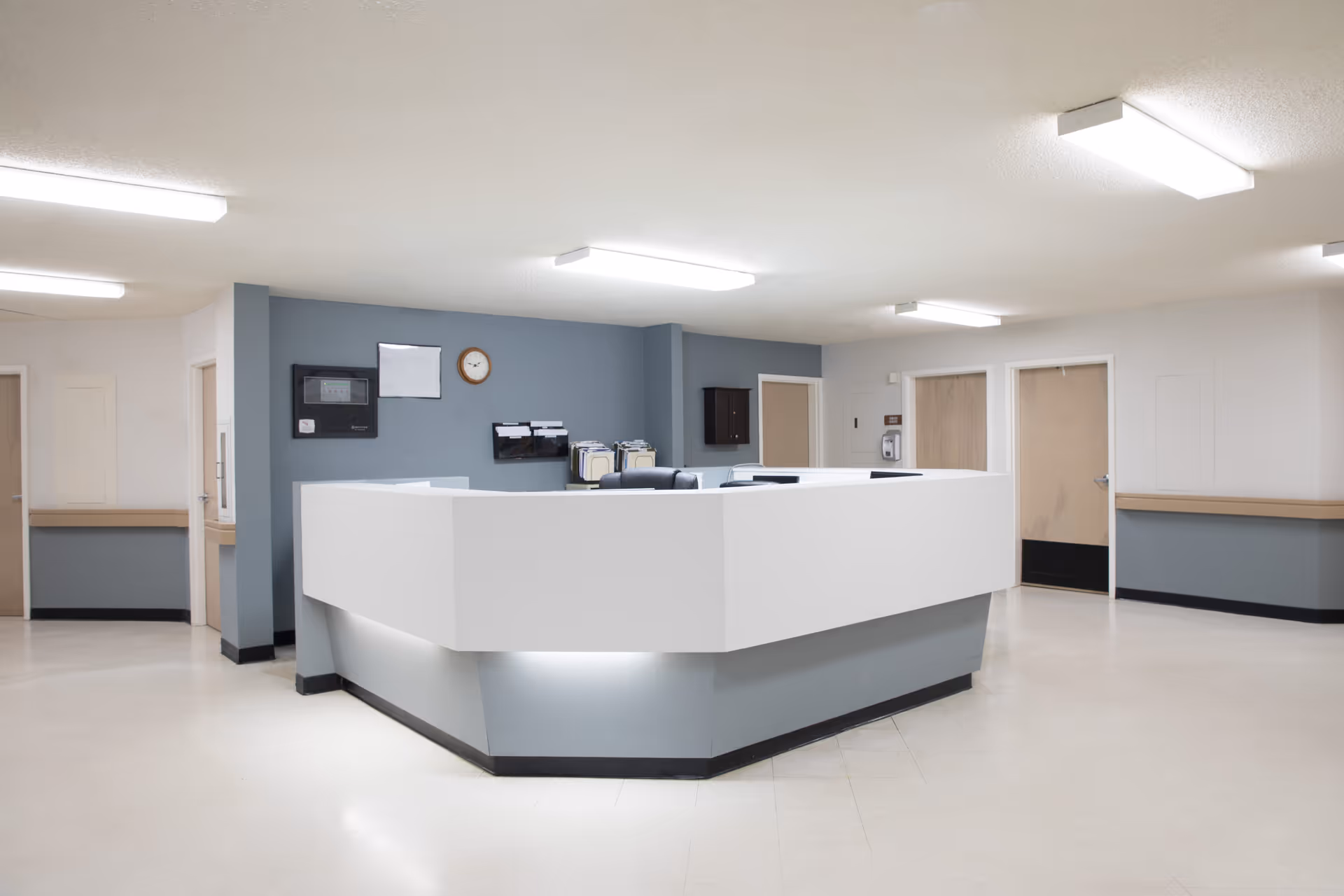 Spacious, well-lit reception desk and nurse station in a senior care facility corridor.