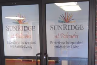 Glass entrance doors with the Sunridge at Palisades logo and text that reads 'Exceptional Independent and Assisted Living.'