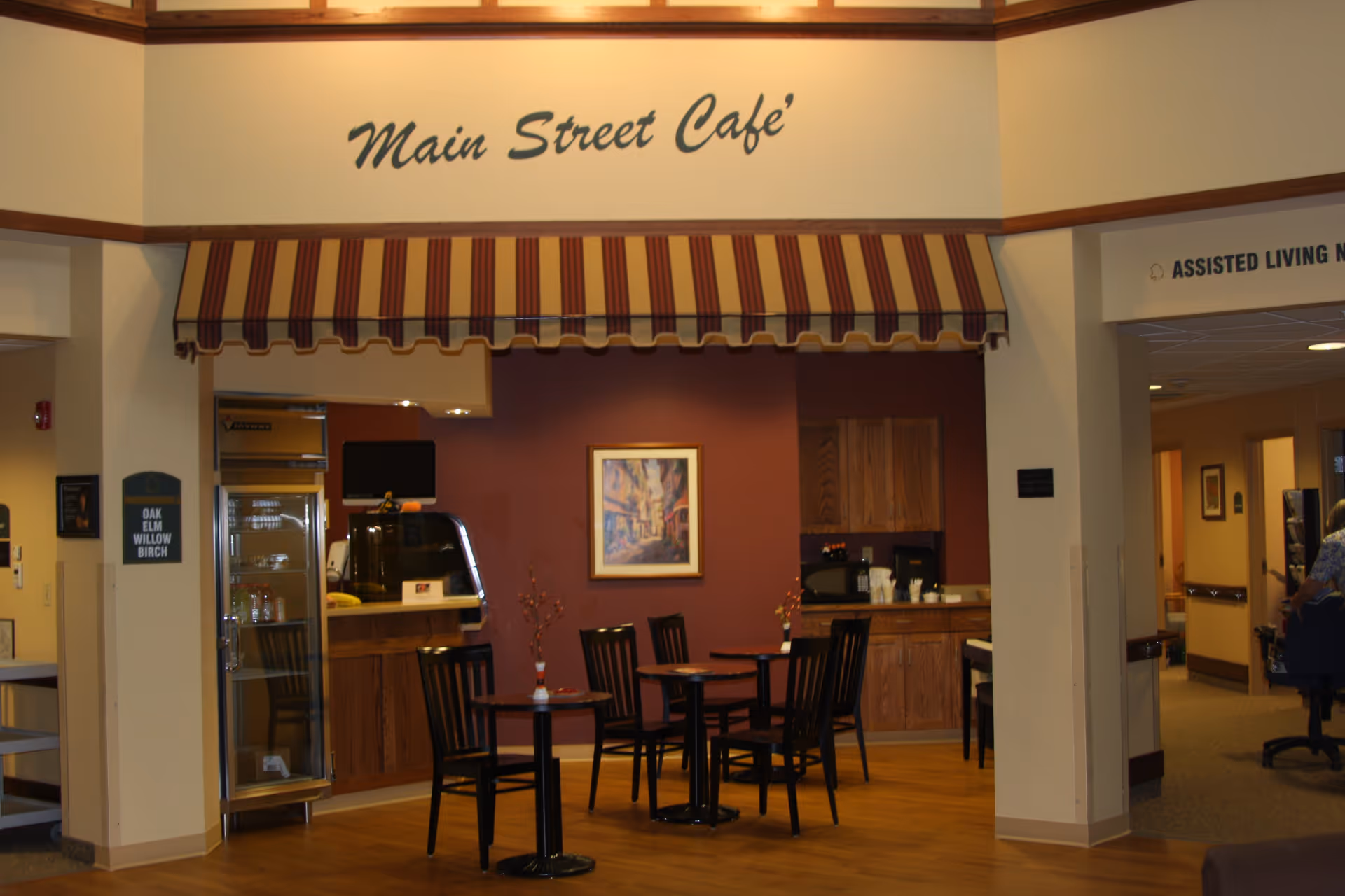 Small indoor café area with tables and chairs under a striped awning and a 'Main Street Café' sign.