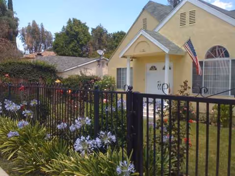 Exterior view of Golden Years III senior living facility with a fence, garden, and flag.