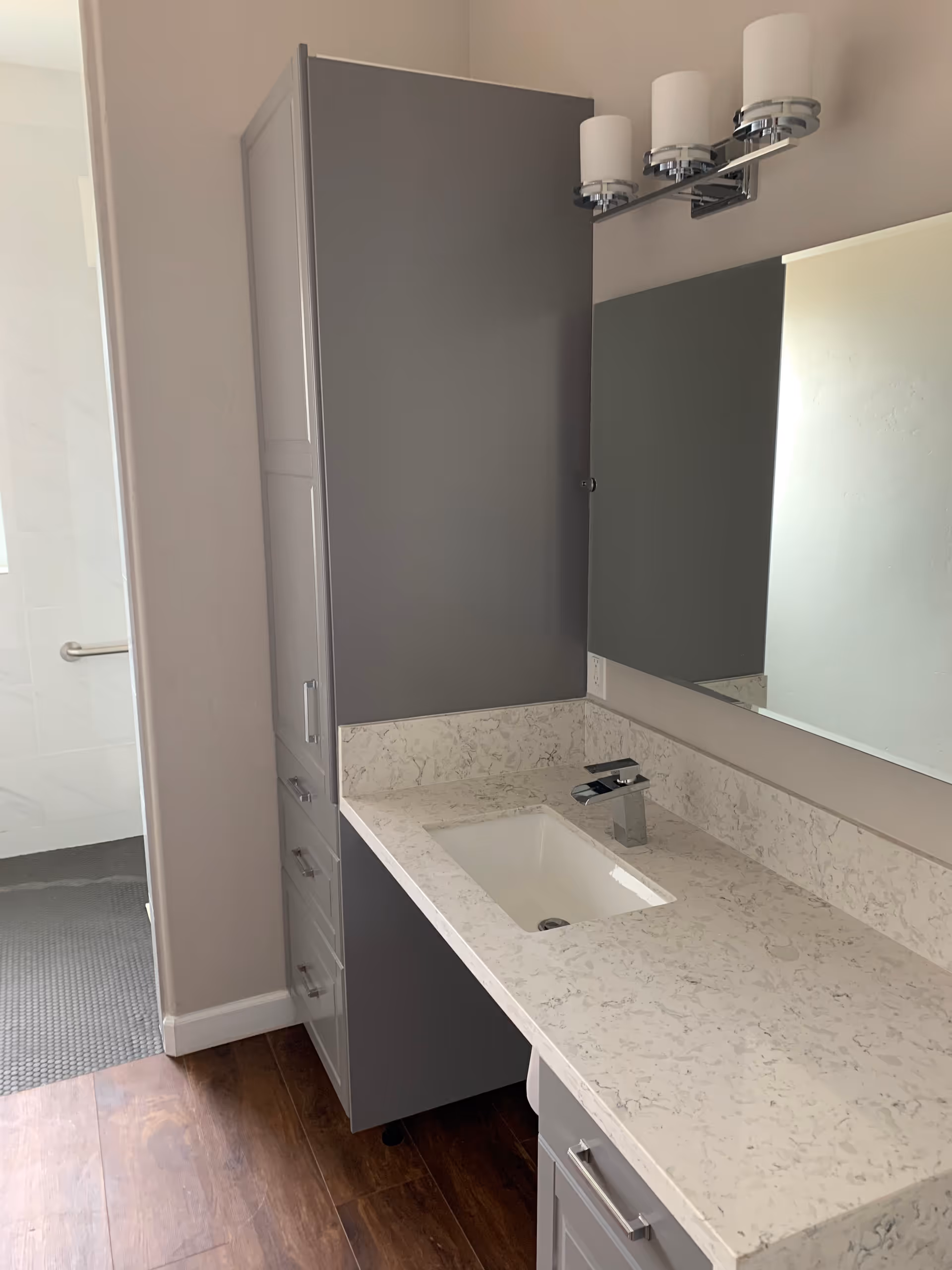 Modern bathroom vanity with a marble-patterned countertop, undermount sink, gray cabinets, mirror, and wall light fixture.