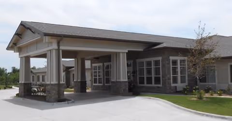 A covered entrance to a modern senior living facility with brick columns and glass windows.