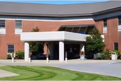 Hartland Park Health & Rehabilitation exterior: brick building with white porte-cochere and shrubs.