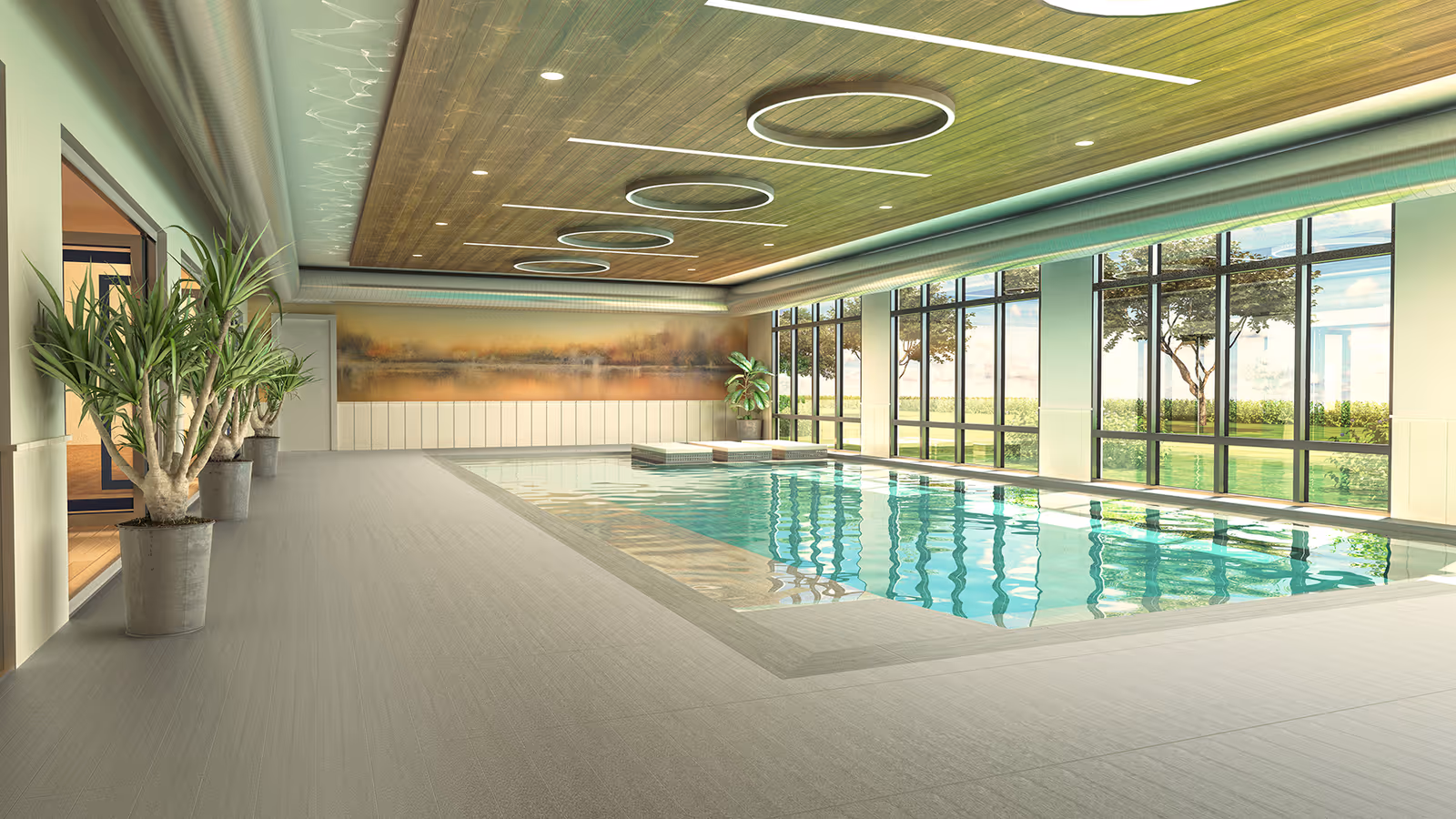 Indoor swimming pool area with large floor-to-ceiling windows showing an outdoor view with trees and grass. The pool is rectangular with clear water, surrounded by light-colored flooring. The ceiling has wooden paneling with circular light fixtures. There are potted plants along the left side near the entrance.