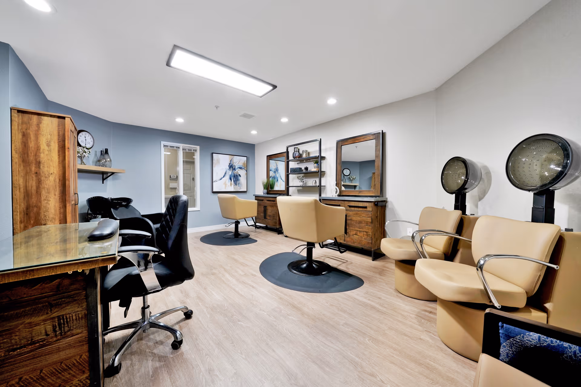 Hair salon room with styling stations, swivel chairs, and hooded dryers.