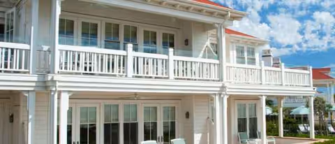 Two-story white senior living facility with balconies and outdoor seating.