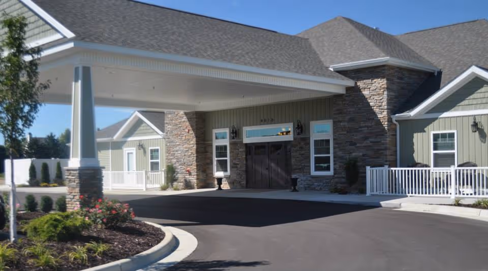 Exterior entrance of a luxury retirement facility with porte-cochere, stone accents, and landscaped driveway.