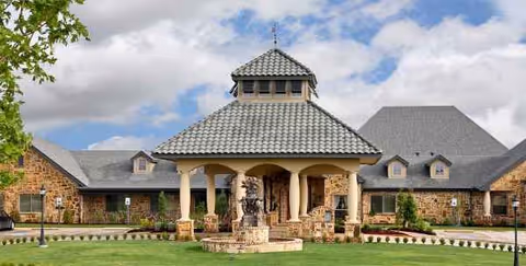Front exterior of a brick senior care building with a central entry and fountain