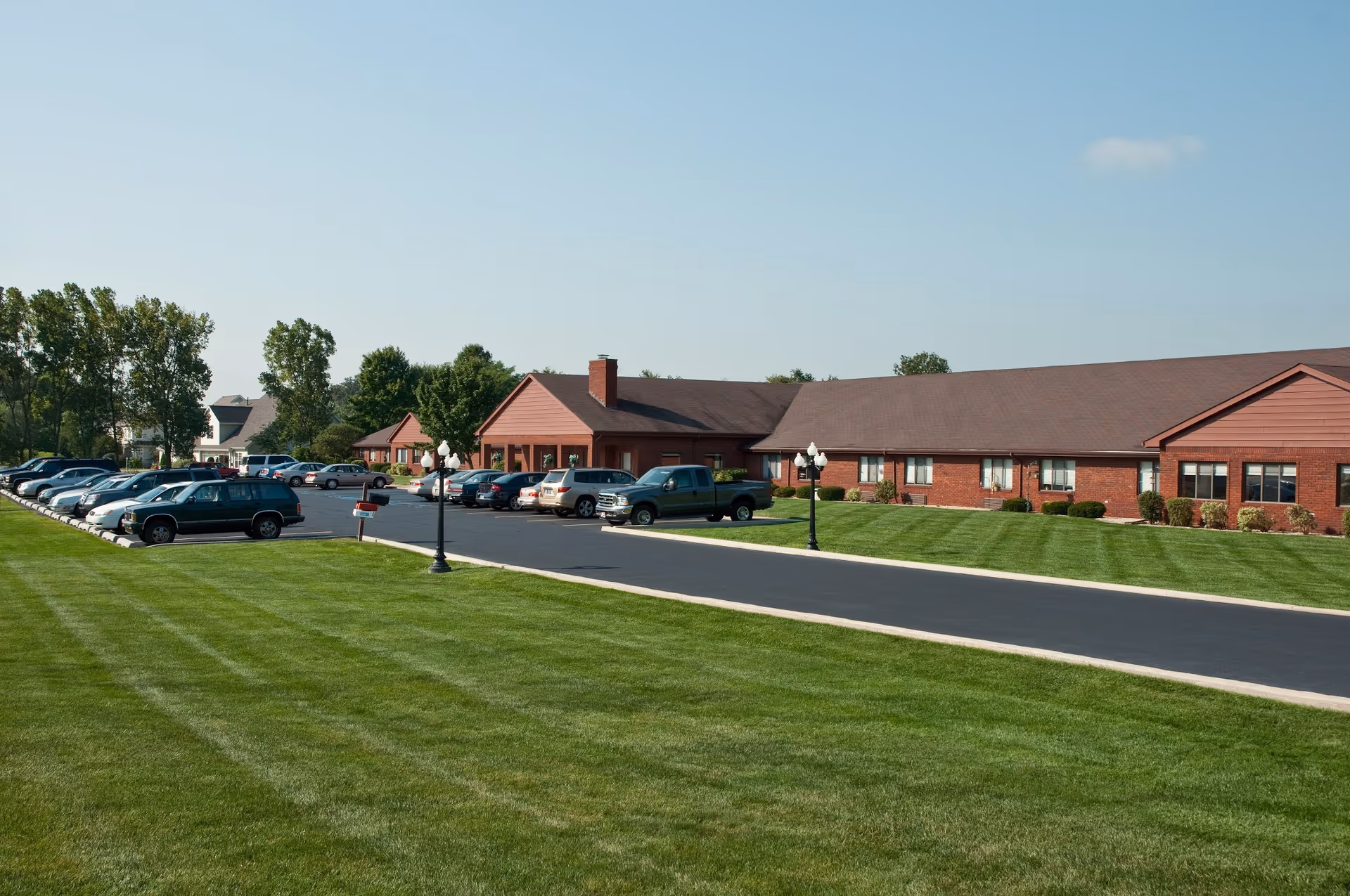 A view of the Life Care Center of Valparaiso featuring parking spaces, well-maintained grass, and the facility buildings.