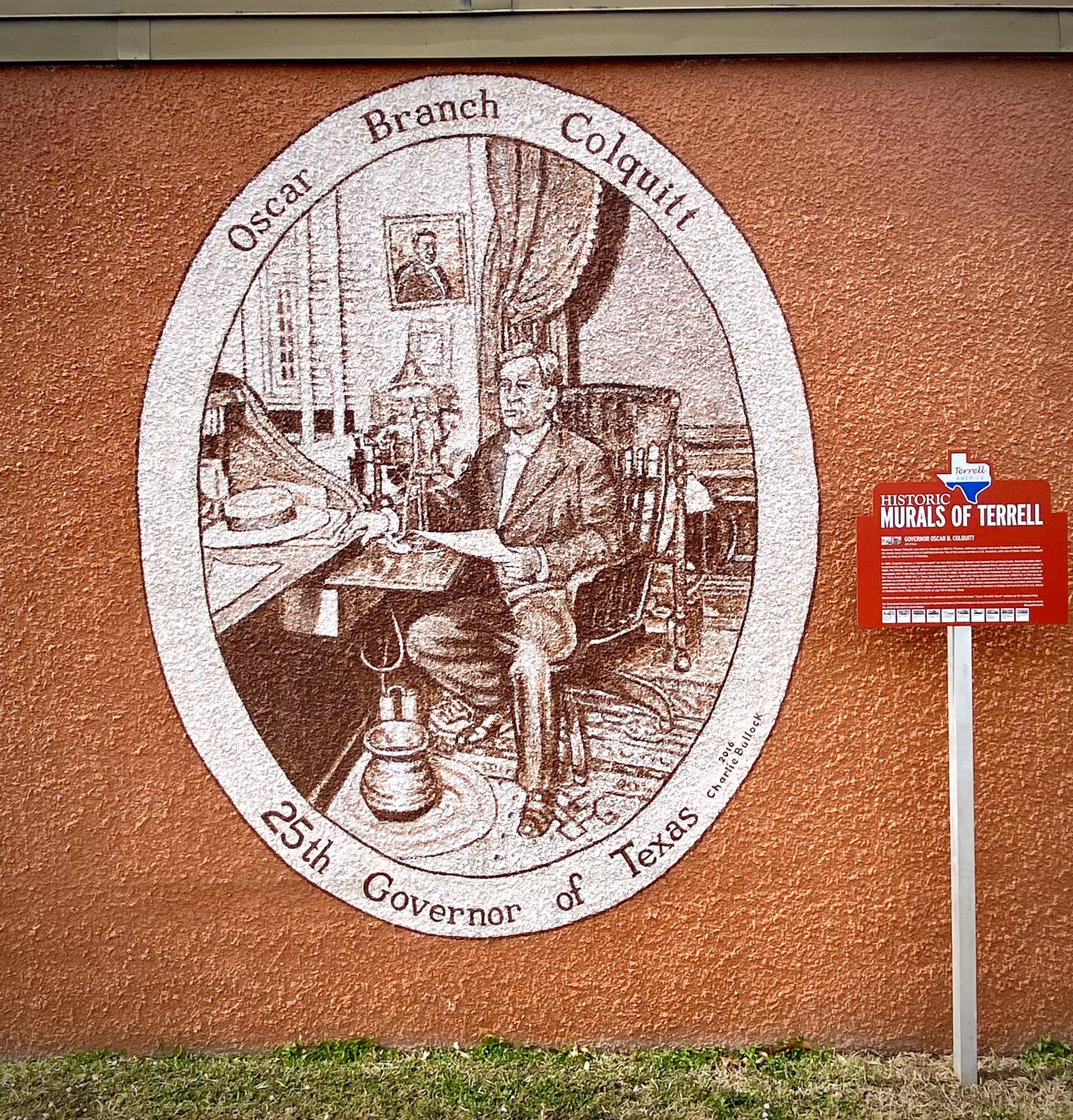 An oval sepia-toned historical mural painted on an orange exterior wall with an informational red "Historic Murals of Terrell" sign to the right.