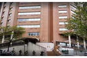 Front exterior of a multi-story healthcare building with stairs, wheelchair ramps, and trees in front.