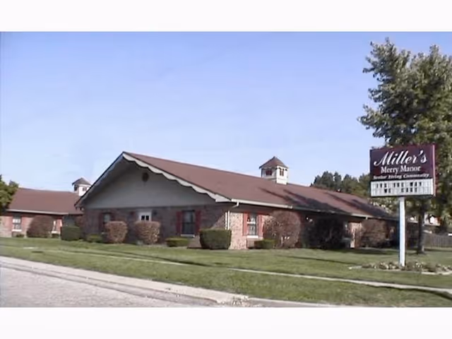 Single-story brick senior living building with a pitched roof and a lawn-mounted sign reading "Miller's Merry Manor".