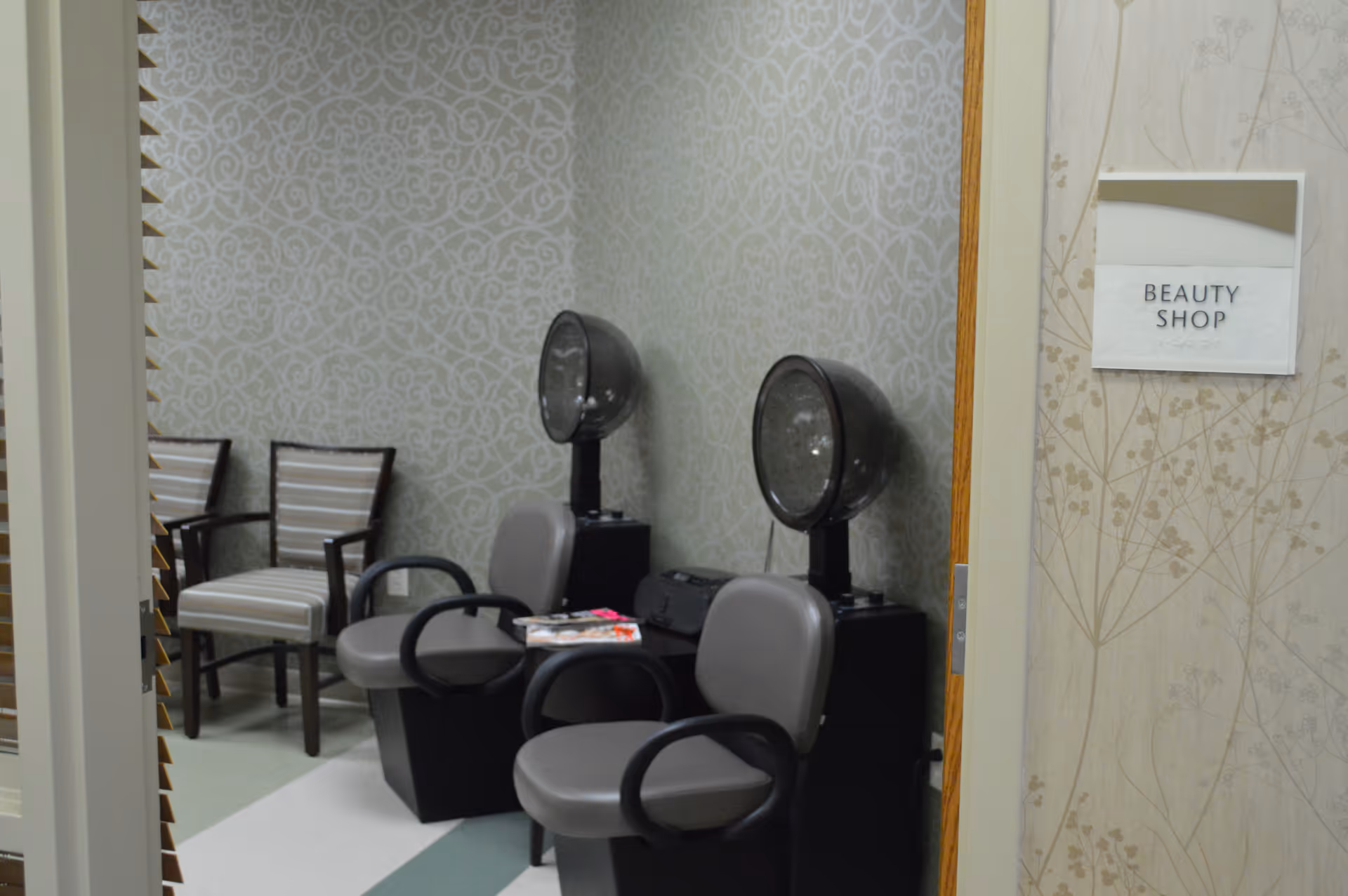 Small beauty shop interior with salon chairs and two hooded hair dryers and a sign reading 'Beauty Shop' on the wall.