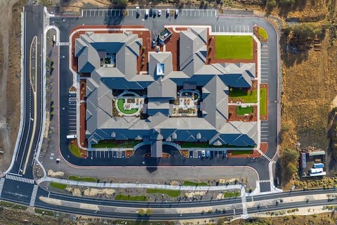 Aerial view of Kiley Ranch Senior Living facility showing the building layout with multiple wings, parking lots surrounding the building, landscaped areas, and adjacent roads.