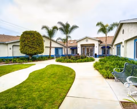 Exterior view of Ivy Terrace at Garden Grove Memory Care with courtyard and benches.
