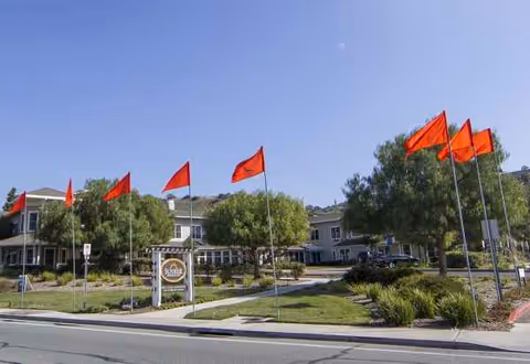Exterior view of Sunrise at Bonita with flags along the entrance and landscaped grounds.